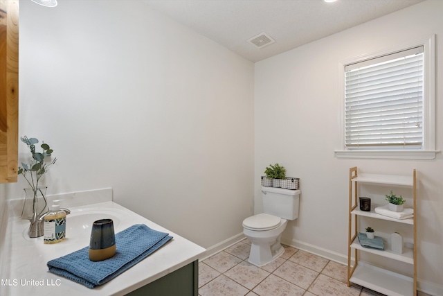 bathroom with toilet, vanity, and tile patterned floors