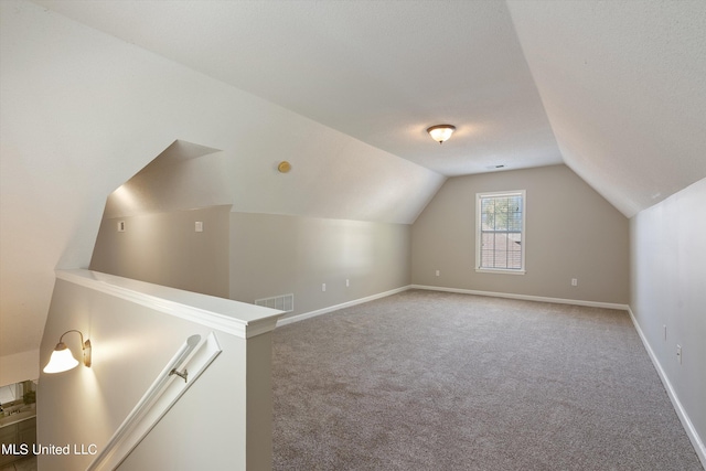 bonus room featuring a textured ceiling, carpet flooring, and vaulted ceiling