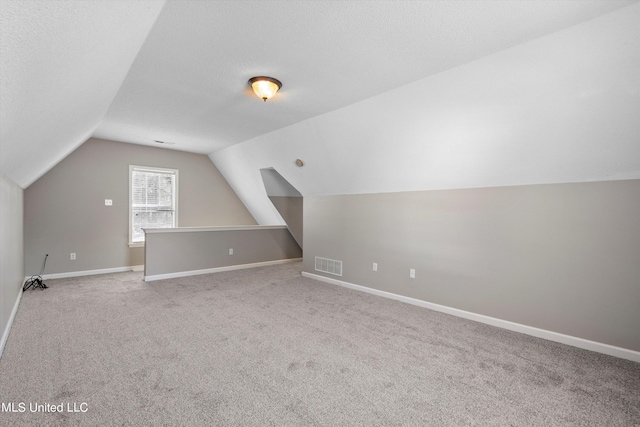 bonus room featuring a textured ceiling, lofted ceiling, and light colored carpet