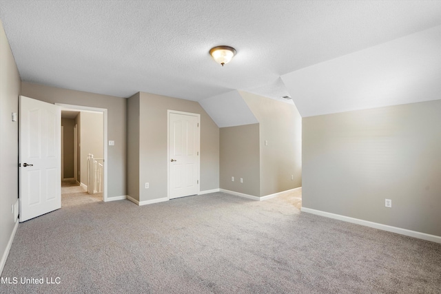 bonus room featuring lofted ceiling, light carpet, and a textured ceiling