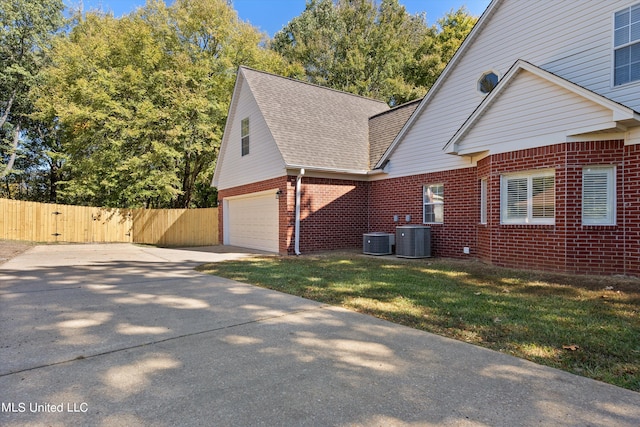 view of side of home featuring central AC unit, a garage, and a lawn