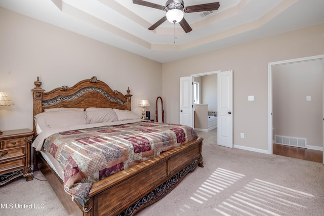 bedroom with ceiling fan, light colored carpet, and a raised ceiling