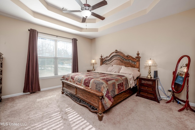 bedroom featuring ceiling fan, light colored carpet, and a tray ceiling