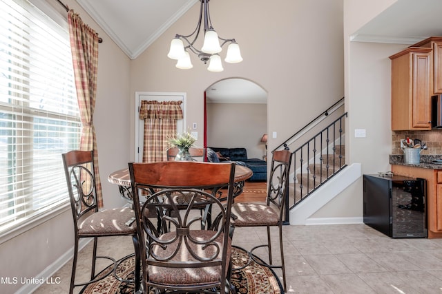 tiled dining area featuring an inviting chandelier, ornamental molding, lofted ceiling, and wine cooler