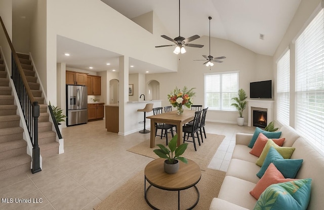 7419 Rose Garden Ln, Olive Branch, MS 38654 - living area with light tile patterned floors, stairs, a warm lit fireplace, arched walkways, and a ceiling fan