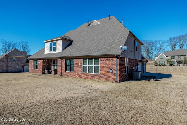 back of house featuring central AC unit, a garage, and a lawn