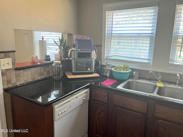 kitchen featuring dark brown cabinetry, backsplash, white dishwasher, and sink