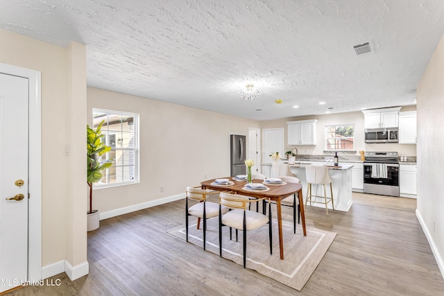 dining space featuring light hardwood / wood-style floors and a textured ceiling