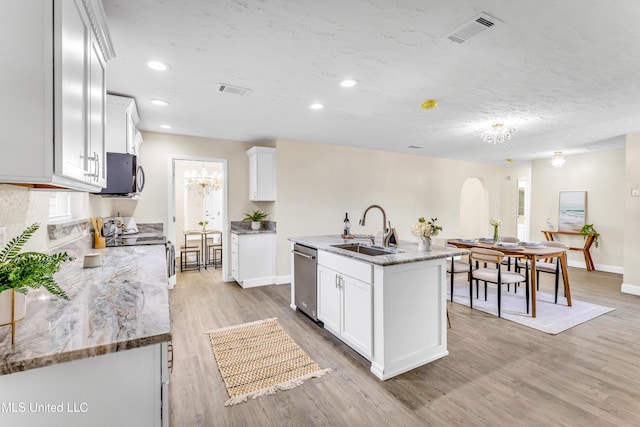 kitchen featuring sink, appliances with stainless steel finishes, light stone countertops, a kitchen island with sink, and white cabinets