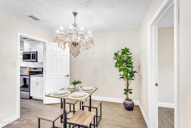 dining space with a chandelier, light hardwood / wood-style flooring, and a textured ceiling