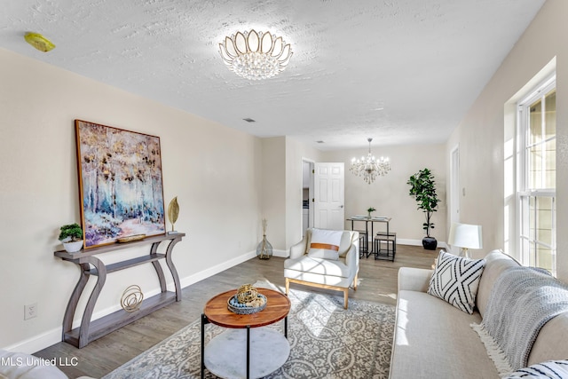 living room featuring a healthy amount of sunlight, hardwood / wood-style floors, a textured ceiling, and a chandelier