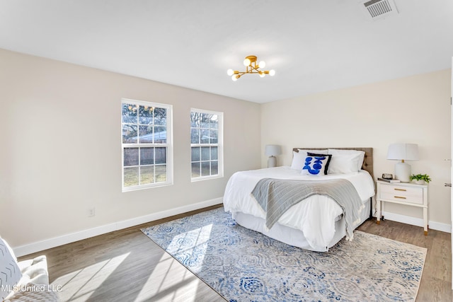 bedroom with wood-type flooring and an inviting chandelier