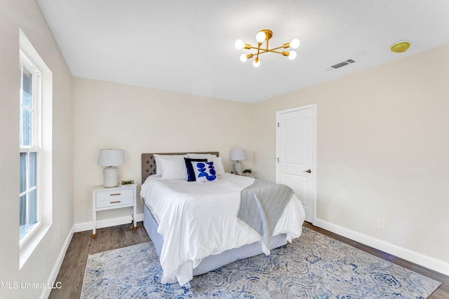 bedroom with a chandelier and dark hardwood / wood-style flooring