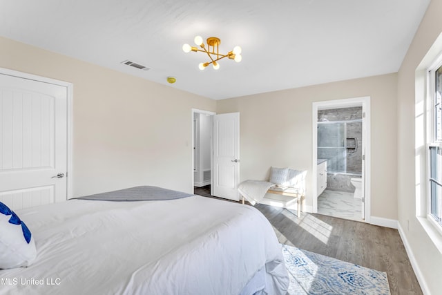 bedroom featuring multiple windows, dark hardwood / wood-style floors, a notable chandelier, and ensuite bath