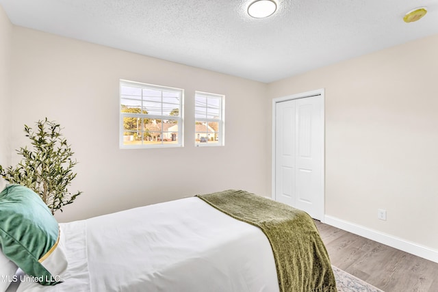 bedroom with hardwood / wood-style flooring, a textured ceiling, and a closet