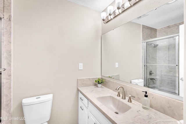 bathroom with vanity, toilet, a shower with shower door, and a textured ceiling