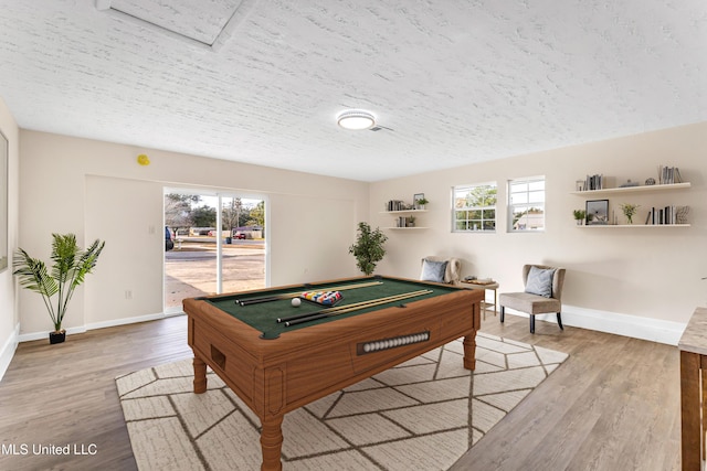 game room featuring billiards, hardwood / wood-style floors, a textured ceiling, and a wealth of natural light