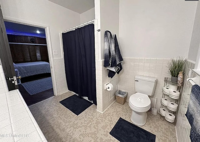 305 Dettor St, Batesville, MS 38606 - ensuite bathroom featuring tile walls, toilet, wainscoting, curtained shower, and tile patterned flooring