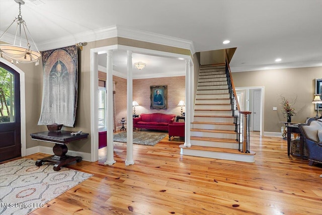 entrance foyer featuring decorative columns, light hardwood / wood-style floors, and ornamental molding