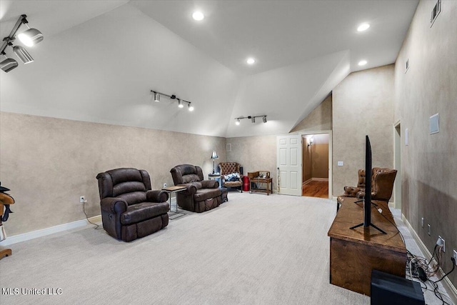 cinema room with high vaulted ceiling, light colored carpet, and rail lighting