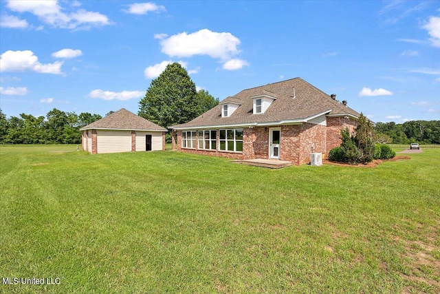 back of property with central air condition unit, an outbuilding, and a lawn