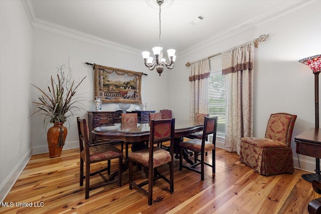 dining area with wood-type flooring, ornamental molding, and an inviting chandelier