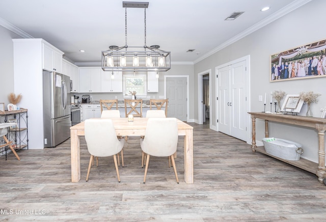 dining space featuring crown molding and light hardwood / wood-style flooring