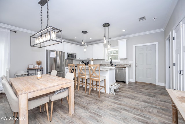 dining space with crown molding and light hardwood / wood-style flooring