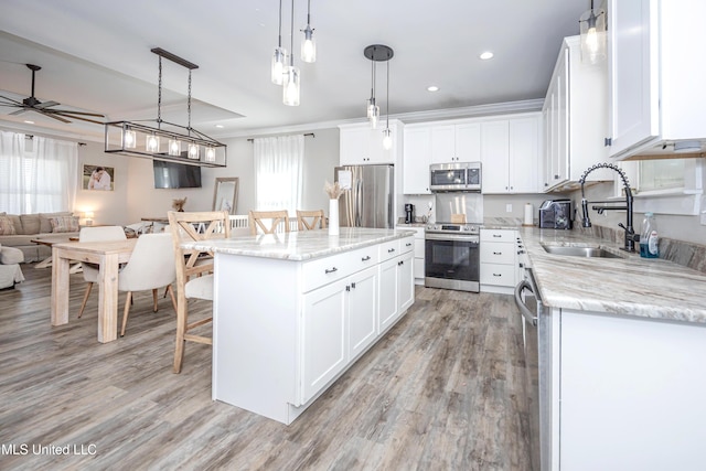 kitchen with appliances with stainless steel finishes, hanging light fixtures, a kitchen island, and white cabinets