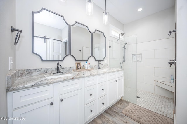 bathroom with vanity, wood-type flooring, and a tile shower