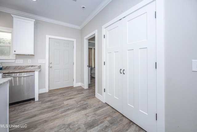 kitchen with crown molding, stainless steel dishwasher, light hardwood / wood-style floors, and white cabinets