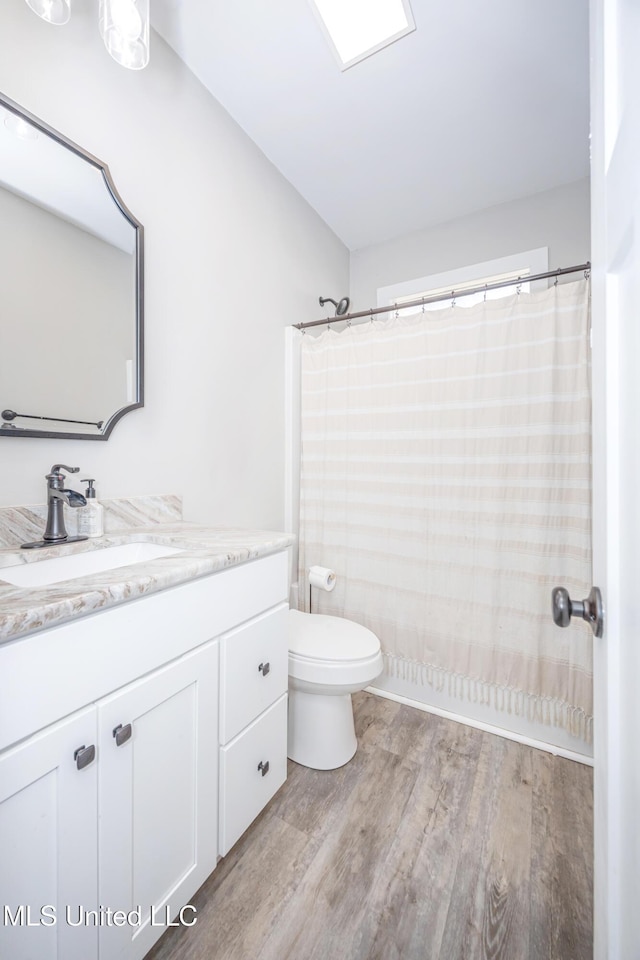 bathroom with hardwood / wood-style flooring, vanity, walk in shower, and toilet