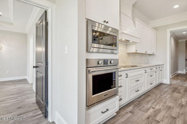 620 Old Savannah Dr, Long Beach, MS 39560 - kitchen featuring stainless steel appliances, custom range hood, light countertops, light wood-style flooring, and white cabinets
