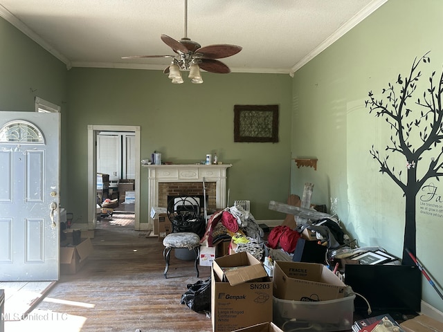 living room featuring ceiling fan, crown molding, hardwood / wood-style floors, a textured ceiling, and a fireplace