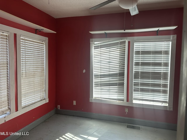 spare room featuring a textured ceiling, concrete floors, and plenty of natural light