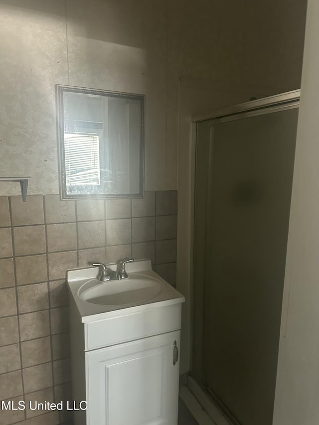 bathroom featuring vanity, tasteful backsplash, tile walls, and a shower with shower door