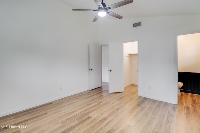 unfurnished bedroom with a closet, ensuite bathroom, baseboards, light wood-style floors, and a spacious closet