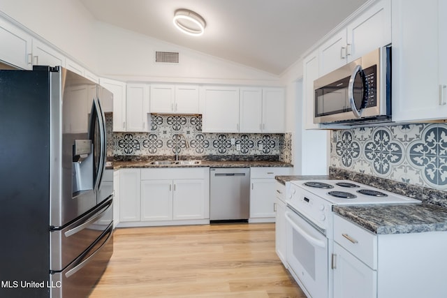 kitchen with a sink, stainless steel appliances, visible vents, vaulted ceiling, and backsplash