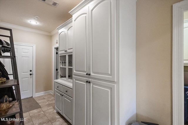 kitchen featuring white cabinetry, ornamental molding, light tile patterned flooring, and a textured ceiling