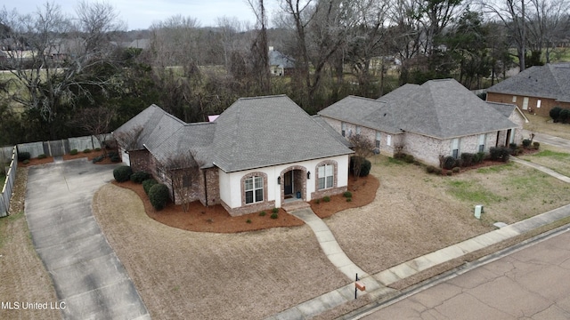 french country inspired facade with fence, driveway, and stucco siding