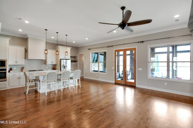 interior space featuring white cabinets, a healthy amount of sunlight, and a center island with sink