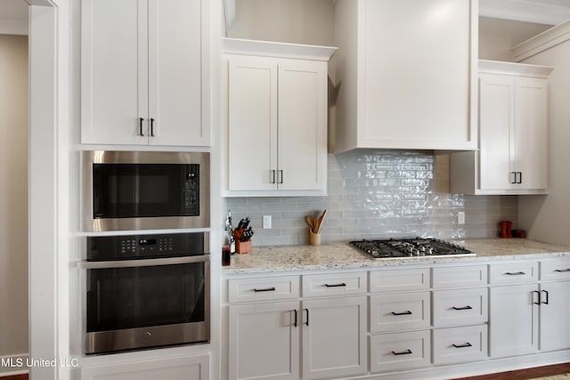 kitchen featuring decorative backsplash, white cabinets, light stone counters, and stainless steel appliances