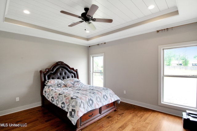 bedroom featuring ornamental molding, ceiling fan, wood-type flooring, and a raised ceiling