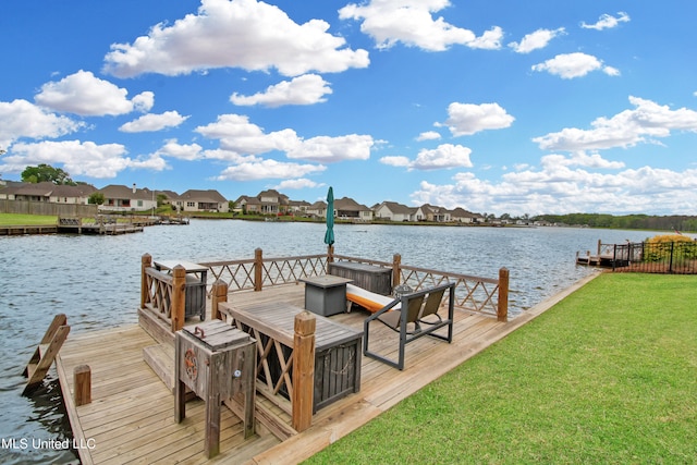 view of dock with a lawn and a water view