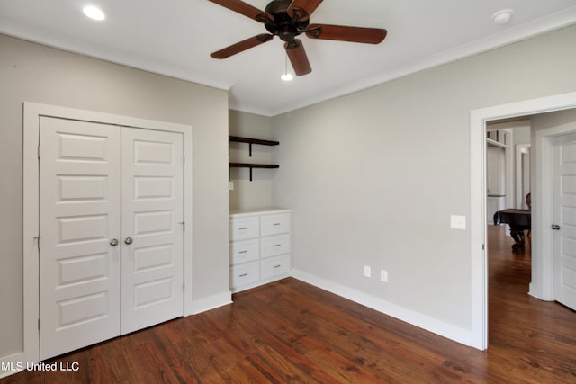 unfurnished bedroom featuring a closet, dark wood-type flooring, crown molding, and ceiling fan