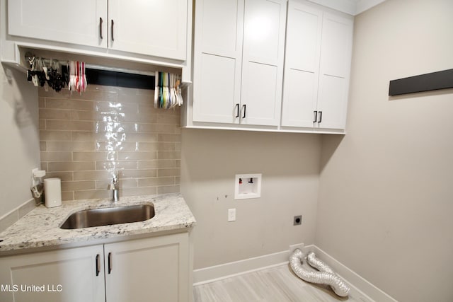 laundry area featuring sink, light hardwood / wood-style floors, electric dryer hookup, washer hookup, and cabinets