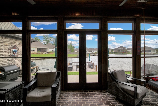 doorway with french doors, brick wall, and a water view