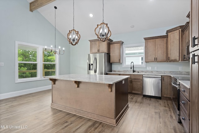 kitchen featuring a breakfast bar, stainless steel appliances, beam ceiling, light hardwood / wood-style flooring, and a kitchen island