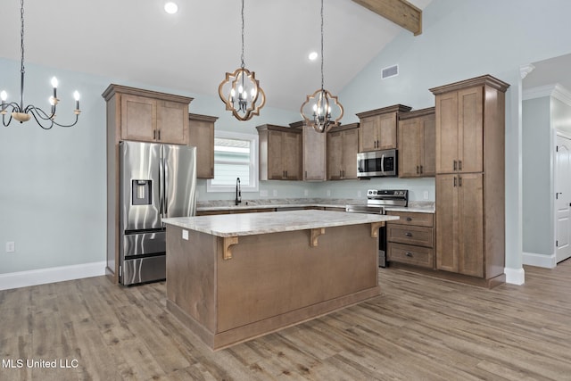 kitchen featuring light hardwood / wood-style flooring, a kitchen island, pendant lighting, and appliances with stainless steel finishes