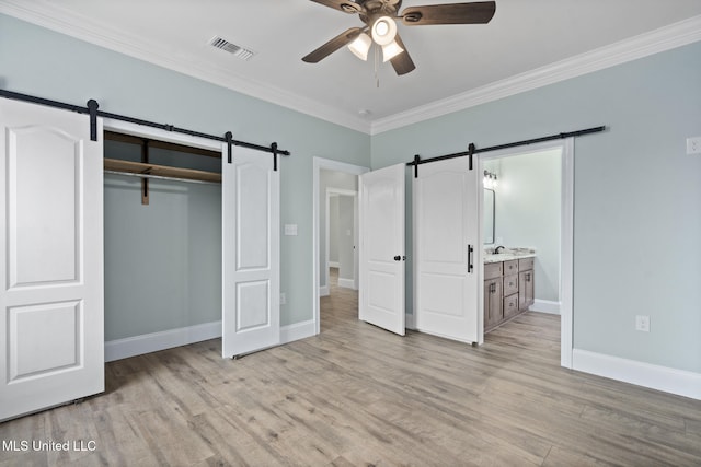 unfurnished bedroom featuring connected bathroom, ceiling fan, light hardwood / wood-style flooring, a closet, and ornamental molding